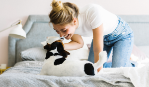 Woman kneeling on a light blue couch petting a cat